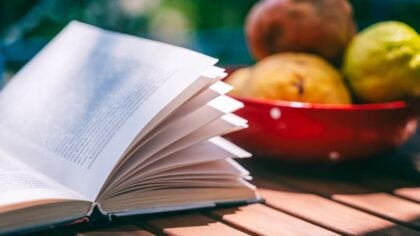 a vegetable gardening book on a table next to a bowl of fruit
