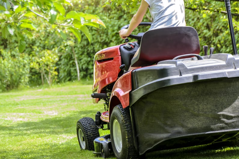 woman mowing a lawn with a riding mower in April